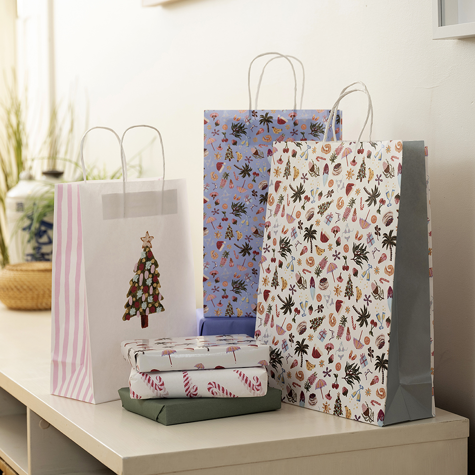 Arrangement of Christmas patterned paper carry bags and wrapped gifts sitting on top of a white cabinet.